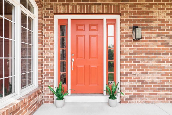 Orange entry door and new windows on a brick house Orange entry door and new windows on a brick house